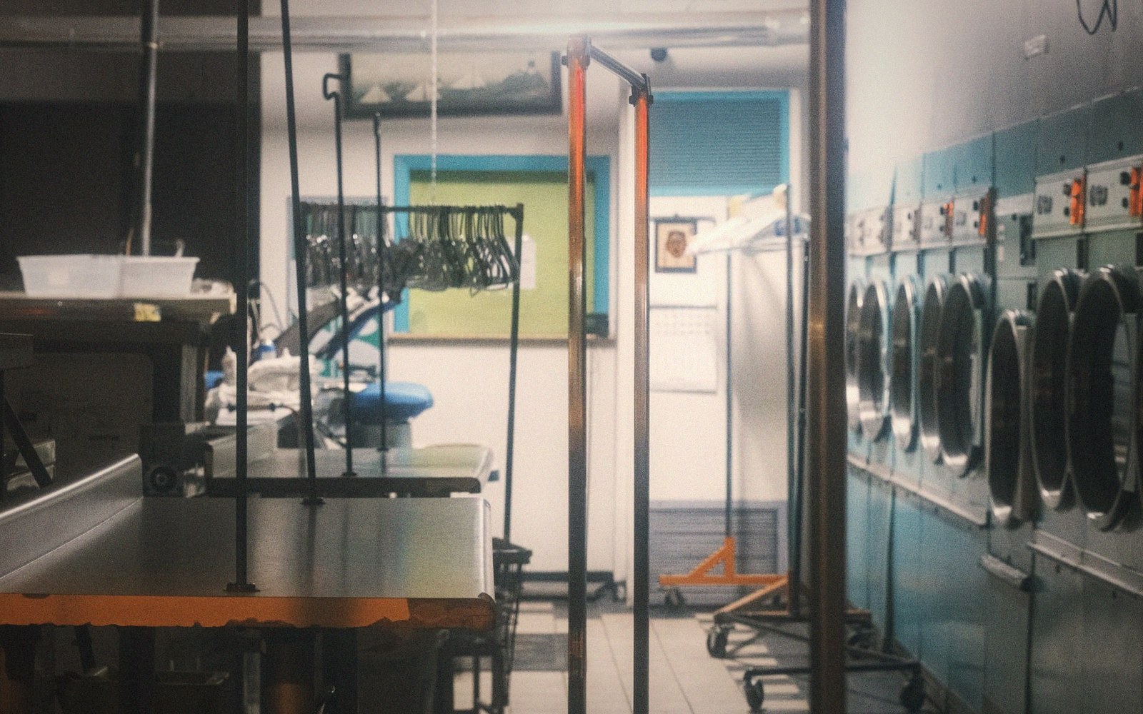 Hotel laundry room with commercial pressing equipment and steam, worker in background