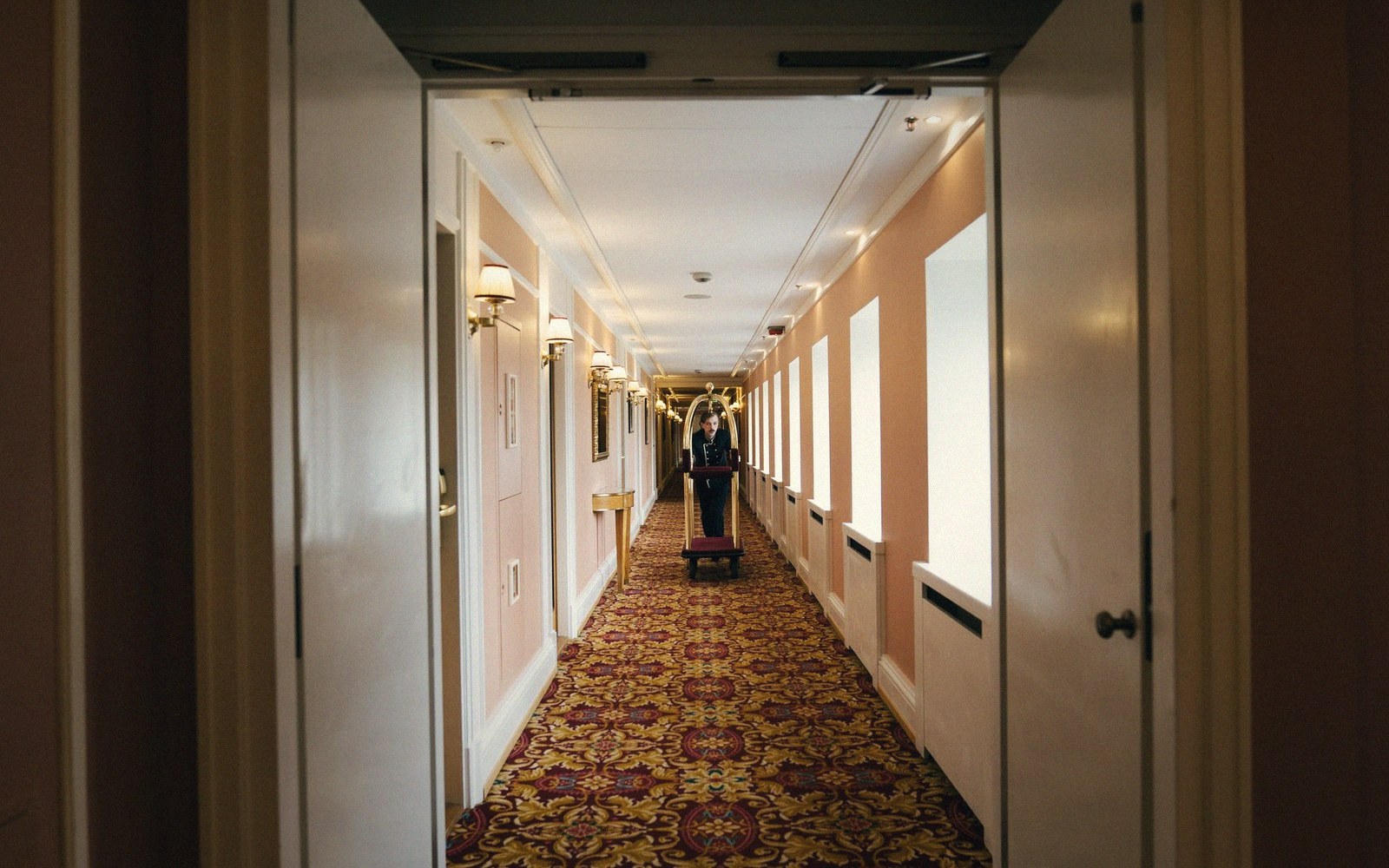 Hotel service corridor with fluorescent strip lighting, linen carts parked against the wall